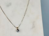 une photo d'un collier orné d'une perle noire
