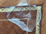 a brown rug with a gold border on a wooden floor