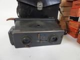 a camera and a briefcase on a table next to a stack of books