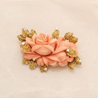 a pink flower with gold leaves and pearls on it