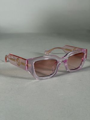 des lunettes de soleil violettes et roses posées sur une surface blanche, sur fond blanc