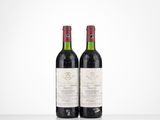 two bottles of red wine sitting on top of a table