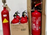 trois extincteurs dans une boîte posée à côté d'un carton