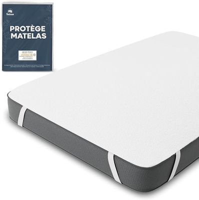 un gros plan d'un matelas posé sur une surface blanche, avec un livre à côté