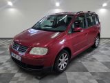 La Volkswagen Caravelle rouge est garée sur un sol en carrelage à damier.
