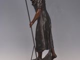 bronze statue of a woman with a broom on a wooden base