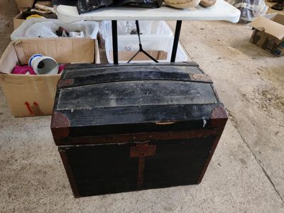 une vieille malle posée par terre à côté d'une table