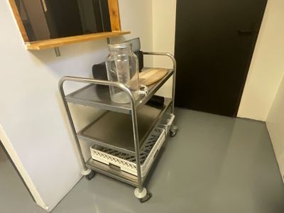 a metal cart with a bottle on it in the corner of a room
