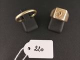 two gold and black cuff rings with a price tag on a black surface