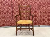 a wooden chair with a yellow seat in front of a red wall
