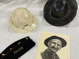deux chapeaux et une carte posés sur un tissu blanc, avec la photo d'un homme coiffé d'un chapeau