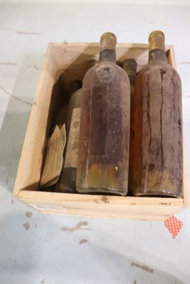 trois bouteilles vides dans une boîte en bois posée sur une table
