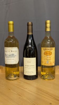 three bottles of wine are lined up on a wooden table