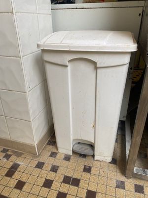 une poubelle blanche posée dans un coin de la cuisine