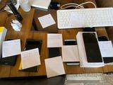 several cell phones and a keyboard on a table with papers
