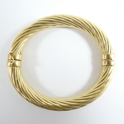 gros plan d'un bracelet en or sur une surface blanche