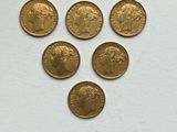 six gold sovereigns are arranged in a triangle on a white surface