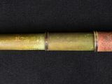 an old brass tube with a red stripe on it