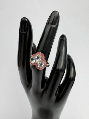 une main noire ornée d'une bague rose et blanche