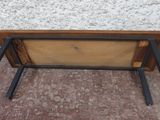un banc en bois avec des pieds en métal posé sur un sol en briques