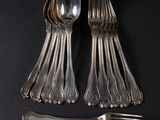 a lot of silver spoons and forks on a black surface