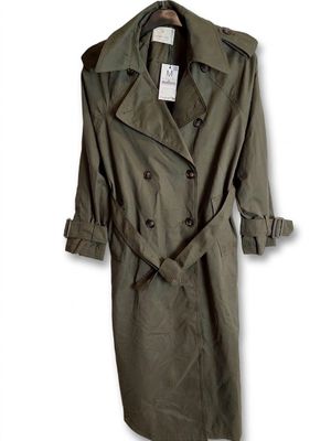 an image of a green trench coat on a hanger on a white wall