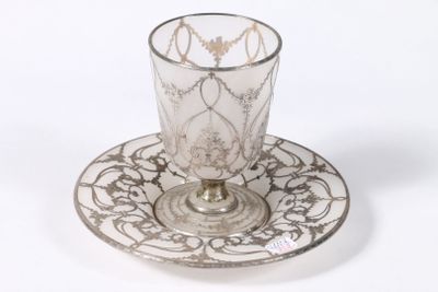 une tasse en verre et sa soucoupe posées sur une soucoupe