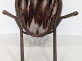 rusty metal chair with wooden seat and legs against a white wall