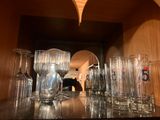bottles and glasses are lined up on a shelf in a room