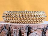 un gros plan d'un bracelet en or posé sur une souche d'arbre