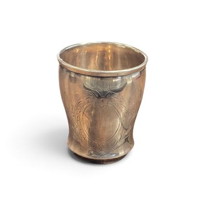 une tasse en argent posée sur une surface blanche