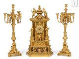 three gold colored candlesticks and a clock on a white background