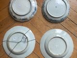 four plates are sitting on a wooden floor next to each other
