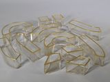 plusieurs morceaux de plastique transparent bordés d'or sur un fond blanc