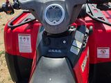a close up of a red motorcycle parked in a field