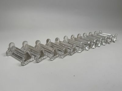 six clear glass toothbrush holders lined up on a white surface