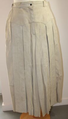 jupe plissée beige posée sur un mannequin devant un mur blanc