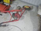 une petite tondeuse à gazon rouge rangée dans un garage