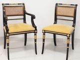 une paire de chaises peintes en noir et or, avec un dossier en rotin