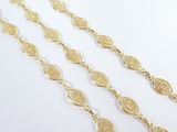 a close up of a gold necklace with a chain on a white surface