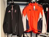 a rack of sports clothing in a store with clothes hanging on it