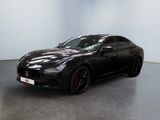 une voiture de carnaval noire garée dans une pièce blanche au sol noir
