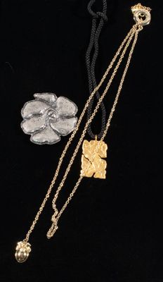 three different necklaces and a coin on a black surface