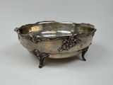 an antique silver bowl with grapes on it on a table