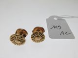 a pair of gold earrings with a tag on a white surface