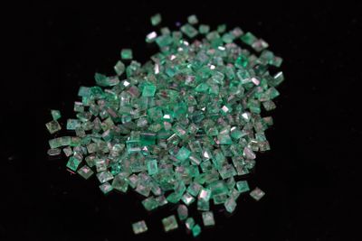 some pieces of green glass sitting on top of a black surface