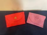 deux pochettes rouges et roses posées sur une table noire