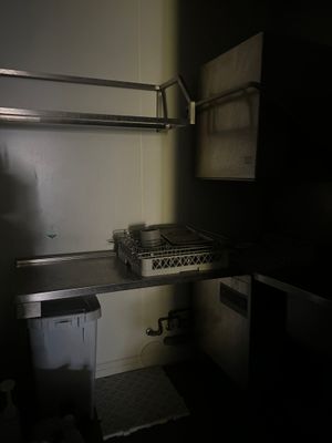 une petite cuisine équipée d'une cuisinière, d'un évier et d'une poubelle