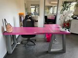 un bureau rose avec une chaise noire dans un coin de la pièce