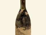 an old bottle of wine sitting on top of a white surface